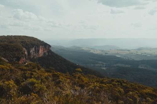 Moody valley view with a rocky cliff face as seen from Blackheath Lookout - Australian Stock Image