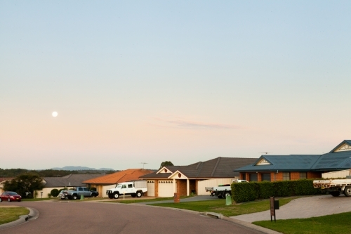 Moon in sky above sleepy town street and residential homes - Australian Stock Image
