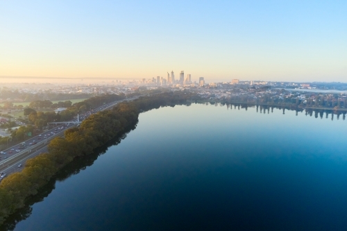 Morning aerial view over Lake Monger with the foggy Perth City skyline and the Mitchell Freeway