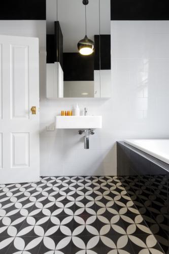 Moroccan styled monochrome bathroom with patterned floor tiles and wall hung vanity - Australian Stock Image