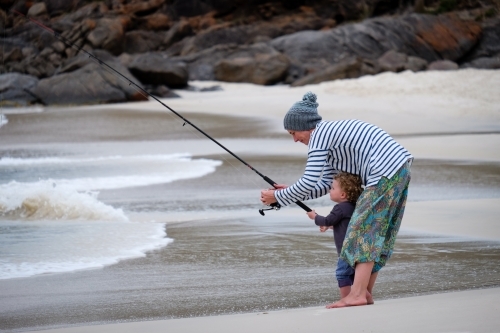 Mother and child fishing at oceans edge - Australian Stock Image