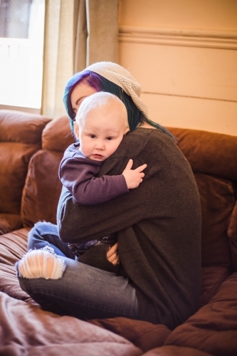 Mother and child sitting on lounge hugging - Australian Stock Image