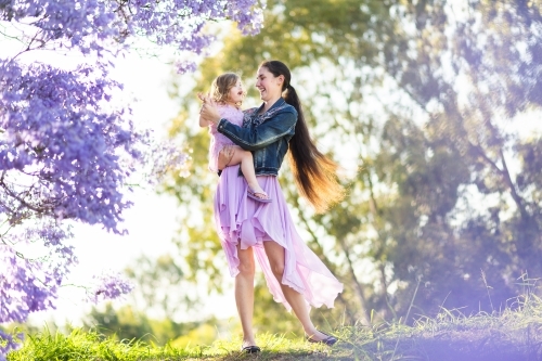 Mother and daughter dancing outside on hilltop with daughter in arms - Australian Stock Image