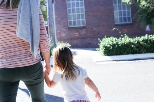 Mother and daughter holding hands while walking - Australian Stock Image