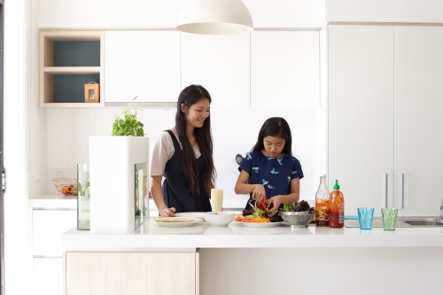Mother and daughter in kitchen cooking together - Australian Stock Image