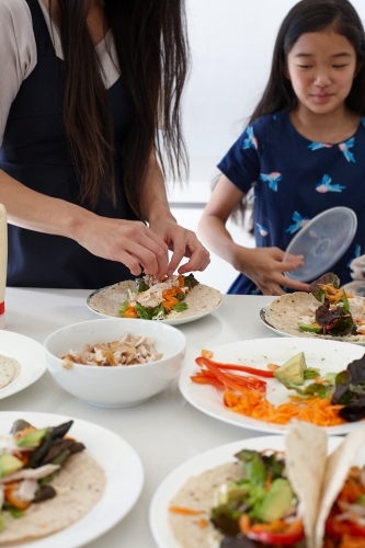 Mother and daughter in kitchen together preparing lunch - Australian Stock Image