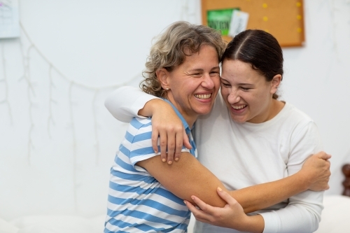 Mother and daughter laughing and hugging - Australian Stock Image