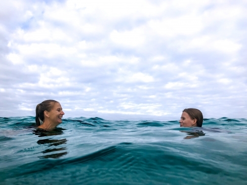 Mother and daughter swimming and playing, looking at each other in the ocean - Australian Stock Image