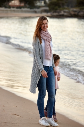 Mother and daughter walking on beach at sunset - Australian Stock Image