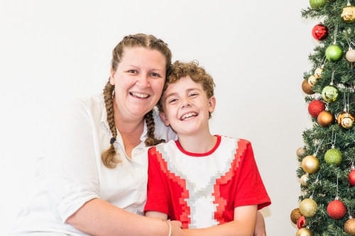 Mother and son laughing together next to Christmas tree - Australian Stock Image