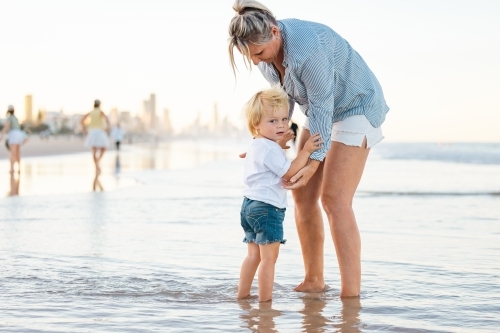 Mother and son playing in shallow water on Gold Coast beach - Australian Stock Image