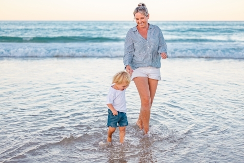 Mother and son playing in shallow water on Gold Coast beach - Australian Stock Image