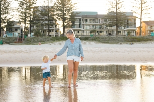 Mother and son playing in shallow water on Gold Coast beach - Australian Stock Image