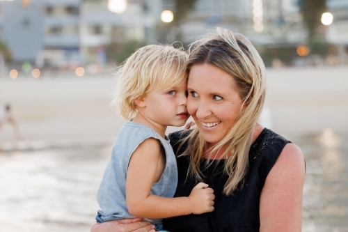 Mother and son snuggling on the beach - Australian Stock Image