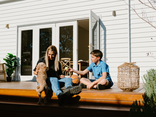 Mother and son spending time outside in the wooden deck. - Australian Stock Image