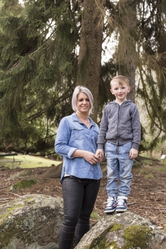 Mother and son standing on a rock surrounded by trees