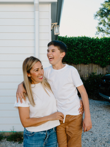 Mother and son standing outside the house laughing. - Australian Stock Image