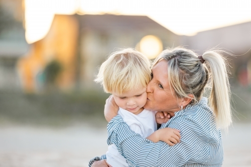 Mother and toddler son embracing on the sand of Gold Coast beach - Australian Stock Image