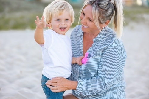 Mother and toddler son embracing on the sand of Gold Coast beach - Australian Stock Image