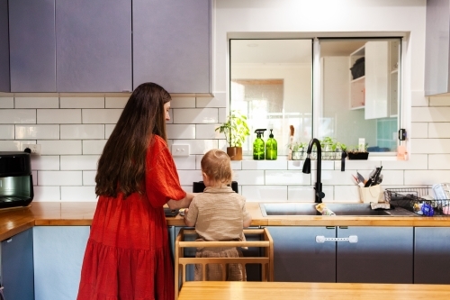 mother and young son cooking together in kitchen doing dinner prep - Australian Stock Image