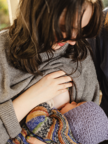 Mother breastfeeding baby wearing beanie - Australian Stock Image