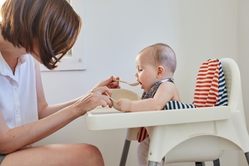 Mother feeding her baby girl solids - Australian Stock Image