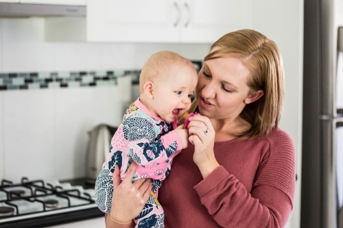 Mother holding baby and giving dummy - Australian Stock Image