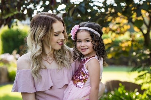 Mother holding daughter on hip smiling - Australian Stock Image