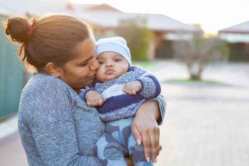 Mother kissing and cuddling her baby boy - Australian Stock Image