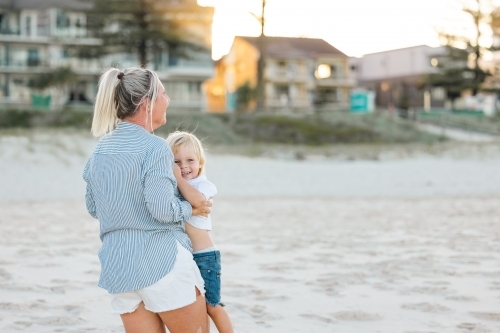 Mother lifting toddler son, playing on Gold Coast beach - Australian Stock Image