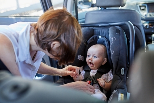 Mother putting baby in a car seat