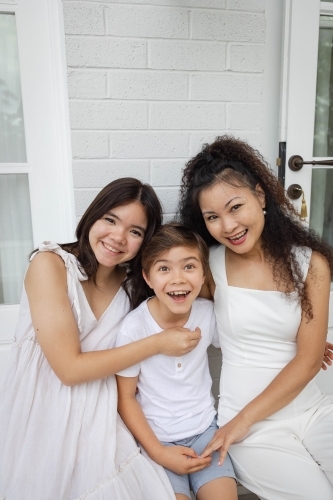 Mother, son and daughter wearing white sitting together - Australian Stock Image