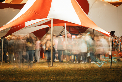 Motion blur crowd of people outside big top circus tent at night - Australian Stock Image