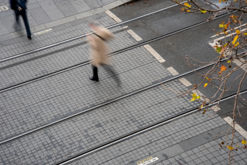 Motion blurred pedestrian crossing tram tracks seen from above - Australian Stock Image