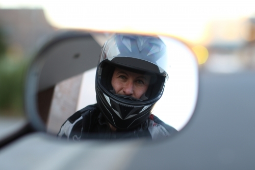 motorbike rider looking in rear view mirror - Australian Stock Image