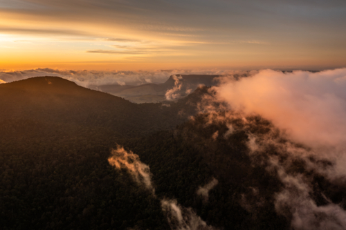 mountain landscape with morning golden light above low clouds - Australian Stock Image