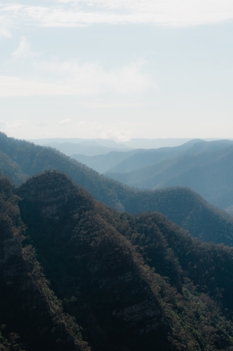 Mountain layers through the valley at Kanangra Walls Lookout on a sunny day - Australian Stock Image