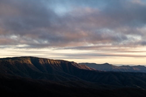 Mountain ranges with morning light and cloudy sky - Australian Stock Image