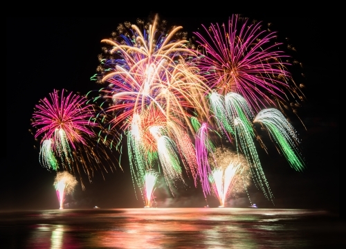 Multi coloured fireworks exploding over an ocean in the night sky. - Australian Stock Image
