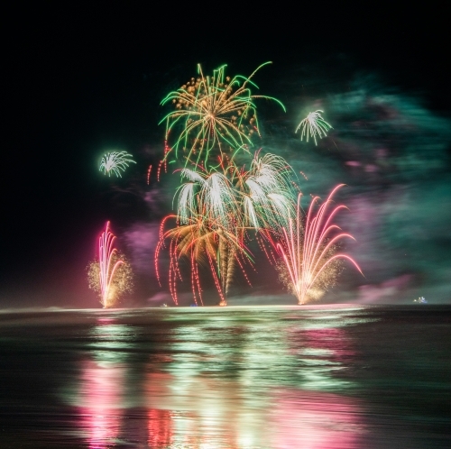 Multi coloured fireworks exploding over an ocean in the night sky. - Australian Stock Image