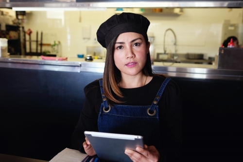 Multicultural Asian waitress taking order at Thai restaurant - Australian Stock Image