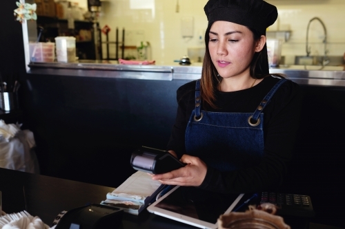 Multicultural Asian waitress taking order at Thai restaurant - Australian Stock Image