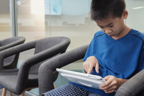 multicultural preteen boy using digital tablet - Australian Stock Image