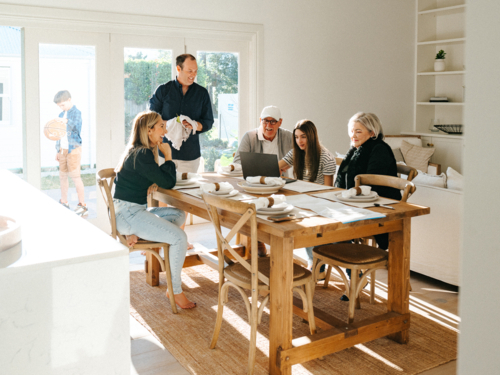 Multigeneration family gathered in the dining table while working on the computer. - Australian Stock Image