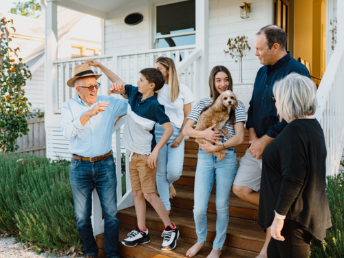 Multigeneration family standing on the steps in front of their house. - Australian Stock Image