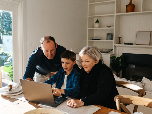 Multigeneration family working in front of a computer. - Australian Stock Image