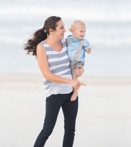 Mum and toddler standing on the beach looking out to the sea. - Australian Stock Image