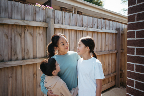 Mum hugging her children outside their house. - Australian Stock Image