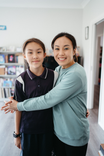 Mum hugging her daughter inside their home. - Australian Stock Image