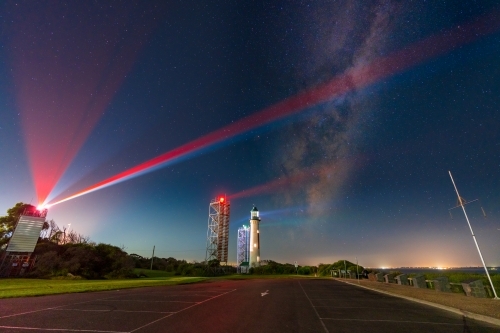 Night time scene of The Milky Way in a starry sky over a lighthouse and beacon towers - Australian Stock Image